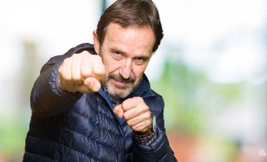 Orta yaş yakışıklı adam kış palto kum yumruk dövüşü, saldırgan ve kızgın saldırı, tehdit ve şiddet giyiyor