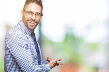 Açık el ile doğal gülümseyen girmek için izole arka plan davet üzerine gözlük takan genç iş adamı