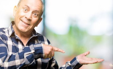 Hayret ve el ile sunulması ve parmak ile işaret ederken kameraya gülümseyen rahat gömlek giymiş yakışıklı komuta sizde.