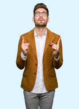 Gözlüklü genç yakışıklı iş adamı şaşırtmak ve yukarıya bakıp parmakları ile işaret şaşırttı ve silah kaldırdı.