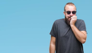 Genç beyaz hipster adam stresli ve gergin elle çivi ısırma ağzına bakarak izole arka plan üzerinde güneş gözlüğü takıyor. Anksiyete sorunu.