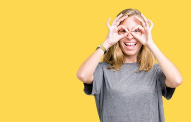 Dilini, parmaklarının arasından baktığını yapışmasını dürbün gibi ok jest yapıyor izole arka plan üzerinde büyük boy rahat t-shirt giyen güzel ve genç birbayan. Deli ifade.