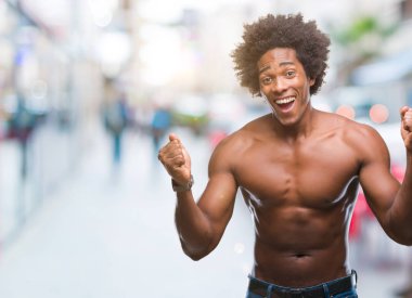 Afro Amerikalı gömleksiz adam çıplak vücut izole arka plan kutlama üzerinde gösterilen şaşırttı ve başarı için kaldırdı kollarını açarak hayret ve gözleri açık. Kazanan kavramı.