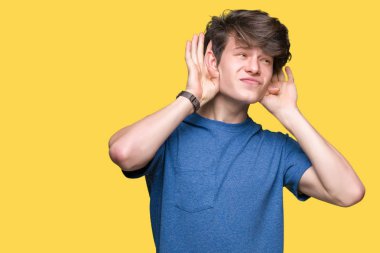 Her ikisi de dinliyoruz izole arka plan üzerinde mavi t-shirt giyen genç yakışıklı adam kulak jest, dedikodu için meraklı eller. İşitme sorunu, sağır