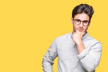 Emin çapraz kollar ve çeneme kaldırdı el ile gülümseme ile kameraya bakarak izole arka plan üzerinde gözlük takan yakışıklı delikanlı. Pozitif düşünce.