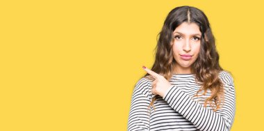 Giyen genç güzel kadın çizgili süveter el parmak ile gösterilen reklam, ciddi ve sakin yüz tarafına işaret