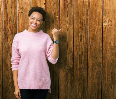 Güzel genç Afro-Amerikan kadın arıyorum ve başparmak yanında yukarıyı mutlu yüz ile gülümseyen izole arka plan üzerinde.