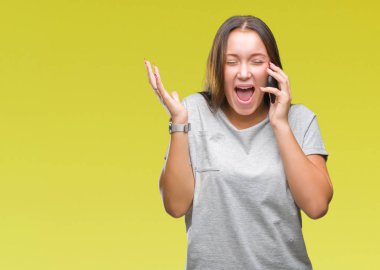 Genç güzel beyaz kadın smartphone üzerinde kocaman bir gülümseme ile çığlık zaferini kutluyor ve ellerini kaldırdı izole arka plan çok mutlu ve heyecanlı, kazanan ifade söz