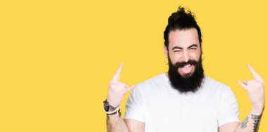 Uzun saç ve sakal deli ifade rock simge elle yapıyor ile rahat beyaz t-shirt bağırarak giyen genç hipster adam. Müzik yıldızı. Ağır kavramı.