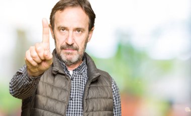 Orta yaş yakışıklı adam giyen kış yelek işaret parmağını ve kızgın ifade ile