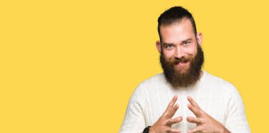 Kış kazak giyen genç hipster adam birlikte elleri ve çapraz rahat ve neşeli gülümseyen parmak. Başarı ve iyimser