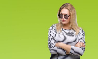 Genç kafkas kadın izole arka plan şüpheci ve sinir, onaylamayan ifade yüz çapraz kolları üzerinde güneş gözlüğü takıyor. Negatif kişi.