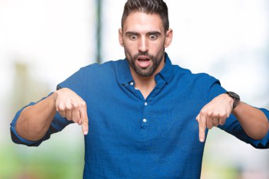 İzole genç yakışıklı adam arka plan işaretleme aşağı reklam, sürpriz yüz ve açık ağız gösterilen parmakları ile