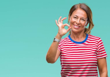 Gülümseyen izole arka plan üzerinde orta yaş İspanyol kadın kıdemli el ve parmaklar ok işaretiyle yapıyor olumlu. Başarılı ifade.