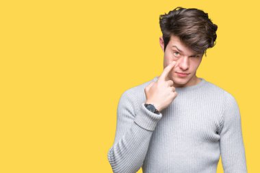 Genç yakışıklı adam giyen kış kazak izole arka plan üzerinde göz izlerken seni jest için şüpheli ifade işaret