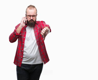 Kızgın yüz, eksi işareti aşağı antipati başparmak ile gösterilen, ret kavramı ile izole arka plan üzerinde Smartphone'da konuşan genç beyaz hipster adam