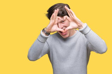 İzole arka plan yaparken kalp şekli el ve parmak işareti seyir gülümseyen ile üzerinde kış kazak giyen genç yakışıklı adam