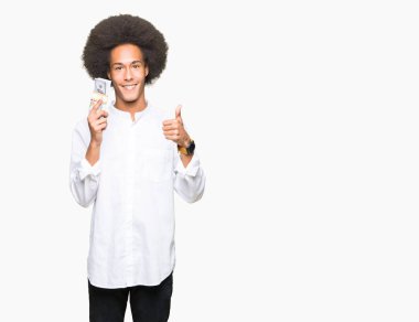 Ok işareti, başparmak ile parmak, mükemmel işareti yapıyor kocaman bir gülümseme ile dolar demet mutlu tutarak afro saçlı genç Afro-Amerikan adam