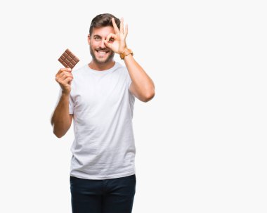 Yakışıklı delikanlı ile mutlu yüz el parmaklarının arasından seyir göz üzerinde ok işaretiyle yapıyor gülümseyen izole arka plan üzerinde çikolata yeme