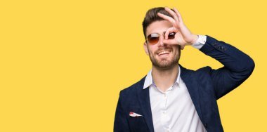 Parmakları ile mutlu yüz üzerinden seyir göz genç yakışıklı zarif adam giyen güneş gözlüğü ve moda ceket el gülümseyen, ok jest yapıyor.