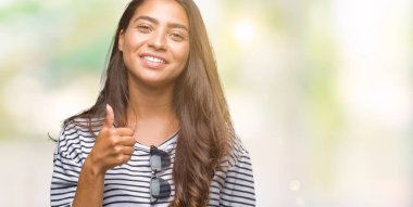 Genç güzel Arap kadın hareketi el ile mutlu yaşasın yapıyor izole arka plan üzerinde güneş gözlüğü takıyor. Kameraya bakarak başarı gösteren ile ifade onaylama.