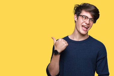 Seyir ve başparmak yanında yukarıyı mutlu yüz ile gülümseyen izole arka plan üzerinde gözlük takan genç yakışıklı adam.
