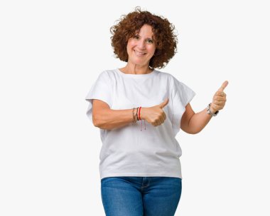 Hareketi el ile mutlu yaşasın yapıyor izole arka plan üzerinde beyaz t-shirt giyen güzel orta ager kadın kıdemli. Başarı gösteren kameraya bakarak ifade onaylama.