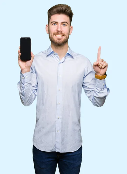 Junger Gutaussehender Mann Zeigt Smartphone Bildschirm Überrascht Mit Einer Idee — Stockfoto