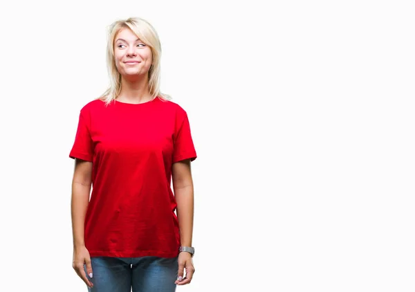 年轻美丽的金发女子穿着红色 T恤衫在孤立的背景微笑看一边 凝视着远离思考 — 图库照片