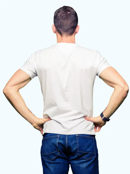 英俊的男人穿着休闲的白色 T恤站在向后看远离手臂上的身体 — 图库照片