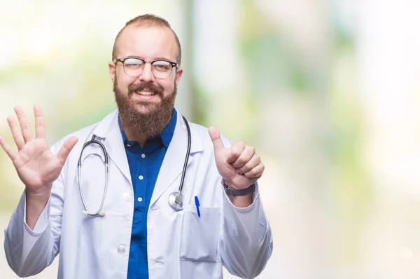 上医療白衣を着ている若い白人医師男分離を示す背景と自信を持って 幸せな笑みを浮かべて 指で上向きナンバーシックス — ストック写真
