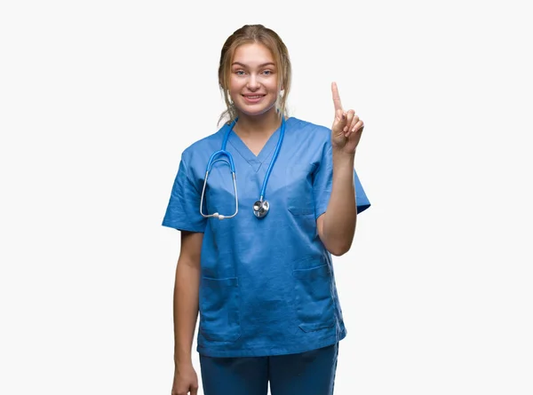 分離背景表示と自信を持って 幸せな笑みを浮かべて 指番号のいずれかで上向きに外科医の制服を着て若い白人医師女性 — ストック写真