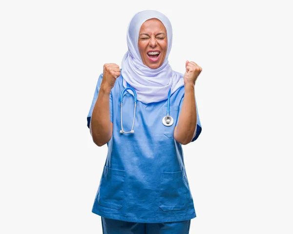 中高年シニア アラブ看護婦非常に幸せと興奮の腕を上げ 勝者のジェスチャを行う分離の背景にヒジャーブを着ている女性 笑顔と成功のために叫んでいます お祝いのコンセプト — ストック写真