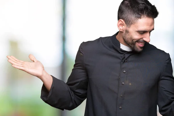 Young Christian priest over isolated background Smiling showing both hands open palms, presenting and advertising comparison and balance