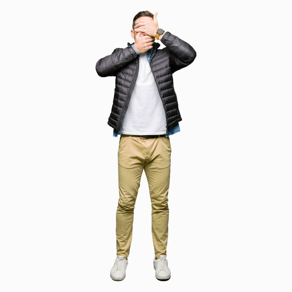 Красивый мужчина в зимнем пальто, закрывая глаза и рот руками, удивлен и шокирован. Скрытие эмоций
