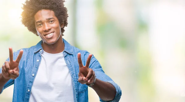 非裔美国男子在孤立的背景下微笑着看着相机显示手指做胜利标志 第二个 — 图库照片