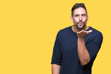 Bir öpücük el ile güzel ve seksi olmak hava üfleme kamera bakarak izole arka plan üzerinde kazak giyen genç yakışıklı adam. Aşk ifade.