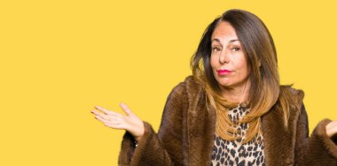 Vizon ceket clueless ve şaşkın bir ifadeyle kollar ve eller kaldırdı giyen güzel orta yaş zarif kadın. Şüphe kavramı.