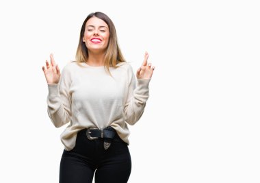Genç güzel kadın rahat beyaz kazak geçiş parmakları umut ve gözleri kapalı ile gülümseyen izole arka plan üzerinde. Şans ve batıl kavramı.