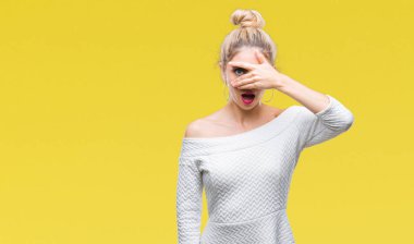 Mahcup ifadeyle parmaklarımın arasından seyir yüz ve gözler el ile kapsayan şok izole arka plan bakmak üzerinde genç güzel sarışın ve mavi gözlü kadın.