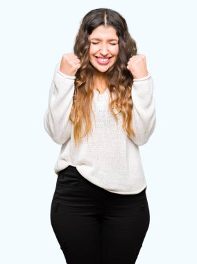 Beyaz kazak silah ile başarı için heyecanlı giyen genç güzel kadın kutluyor zafer gülümseyen kaldırdı. Kazanan kavramı.