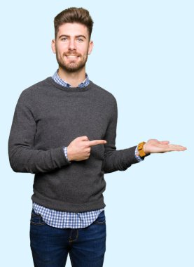 Hayret ve el ile sunulması ve parmak ile işaret ederken kameraya gülümseyen genç yakışıklı zarif adam.