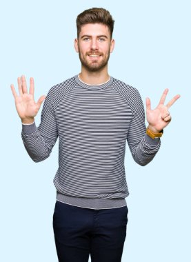 Genç yakışıklı adam giyen çizgili süveter gösterme ve parmakları ile işaret kendinden emin ve mutlu gülümseyerek süre sekiz numara.