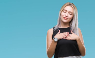 Sarışın genç kadın ile gülümseyen izole arka plan üzerinde kapalı gözler ve yüzünde minnettar jest ile göğüs üzerinde eller. Sağlık kavramı.