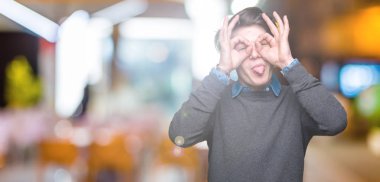 Genç yakışıklı zarif adam izole arka plan, dilini parmaklarının arasından baktığını yapışmasını dürbün gibi ok jest yapıyor. Deli ifade.