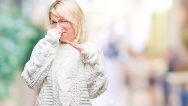 Kış kazak ve gözlük giyen bir şey pis ve iğrenç kokulu izole arka plan, dayanılmaz koku, holding nefes burun parmaklar ile genç güzel sarışın kadın. Kötü kokuyor kavramı.