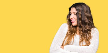 İkna ve kendine güvenen genç güzel kadın giyiyor beyaz kazak tarafına silahlarla seyir gülümseyen geçti