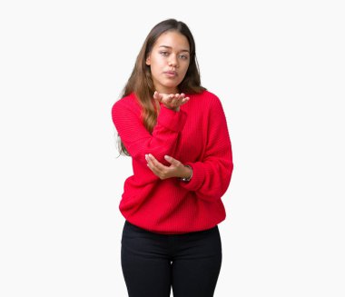 Bir öpücük el ile güzel ve seksi olmak hava üfleme kamera bakarak izole arka plan üzerinde kırmızı kış kazak giyen genç güzel esmer kadın. Aşk ifade.