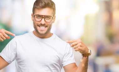 Yüzünde gülümseme ile kendinden emin görünüyorsun, kendini gururlu ve mutlu parmakları ile işaret izole arka plan üzerinde gözlük takan genç yakışıklı adam.