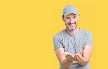 Yakışıklı orta yaş ağarmış kıdemli giyiyor spor kap üzerinde izole adam arka plan gülen alma veya jest vererek birlikte el avuç içi ile. Ayrı tutma ve koruma